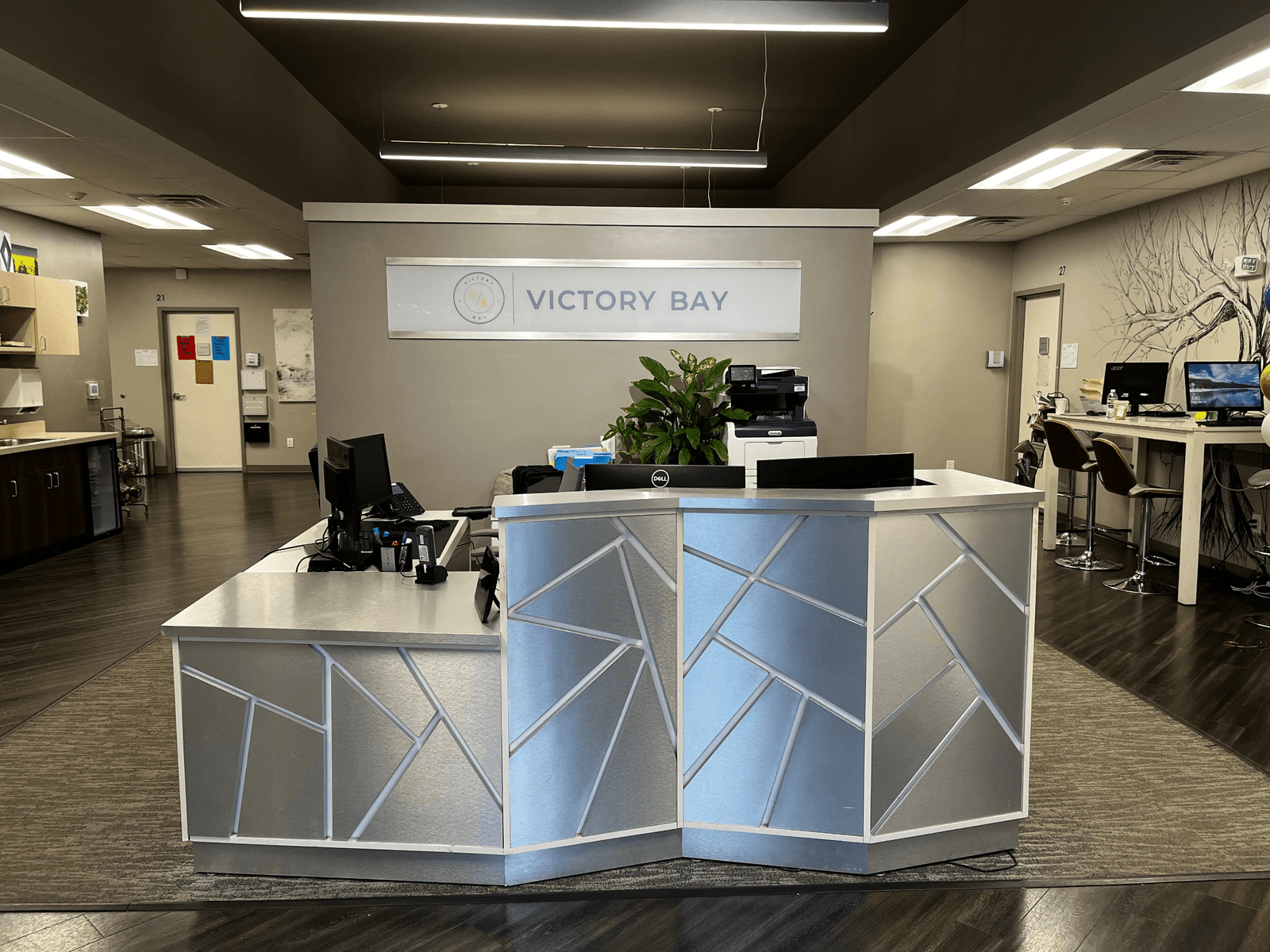 Victory Bay facility reception lobby with an angular white front desk beneath a backlit Victory Bay logo sign