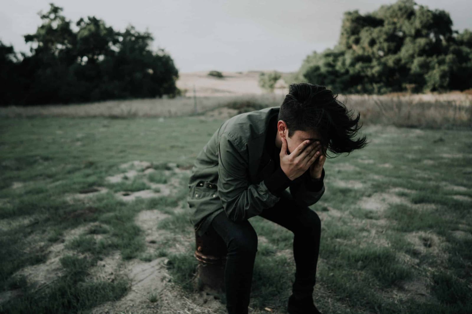 Distressed young man standing alone in a field, representing depression and anxiety